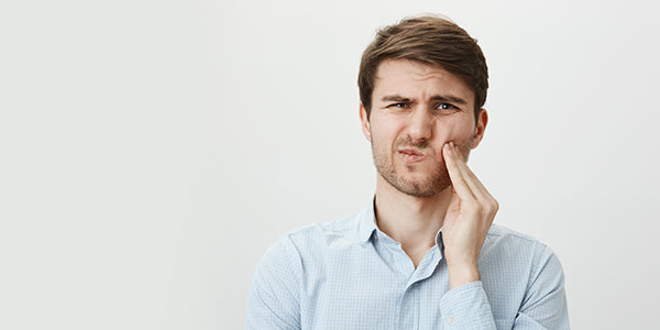 A person experiencing discomfort from hot, cold, sweet, or acidic foods. The text discusses the causes of sensitive teeth, tips for managing the condition, and effective remedies.