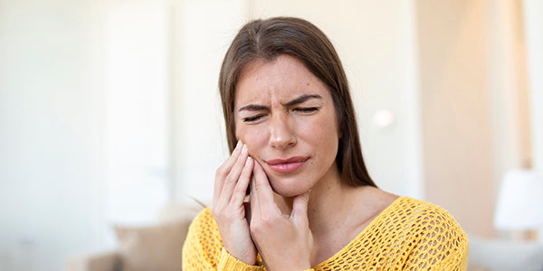 A girl holding her face and showing signs of discomfort, indicating teeth pain.